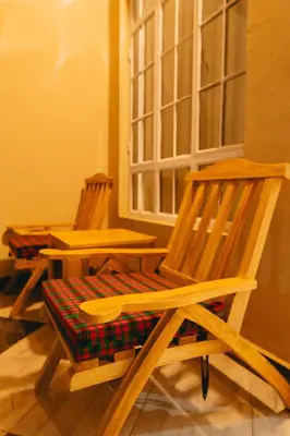 two wooden chairs sitting next to a window at FREEDOM homes in Arusha