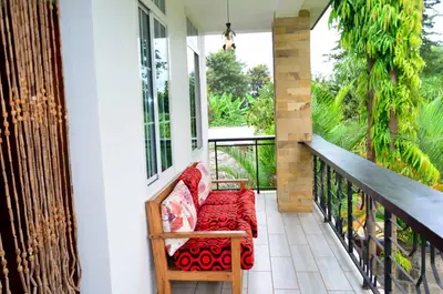 a porch with a bench with a red blanket at Chaga African Home in Moshi