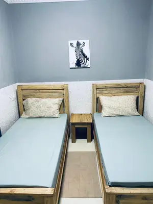 two beds in a room with a picture of a zebra at Tulivu house in Arusha