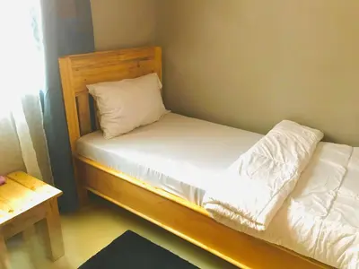 a small bedroom with a bed with white sheets and a pillow at Tulivu house in Arusha