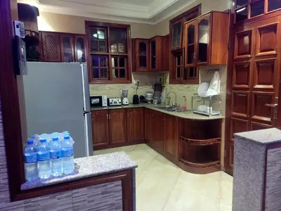 a kitchen with wooden cabinets and a refrigerator with water bottles at Cape Villa in Arusha