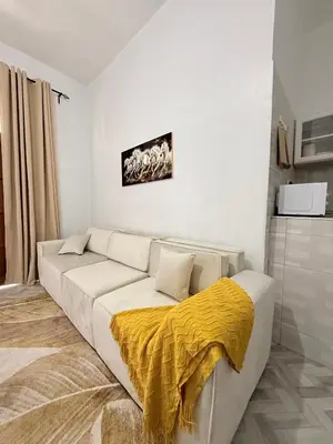 a living room with a white couch with a yellow blanket at Haven Retreat in Arusha