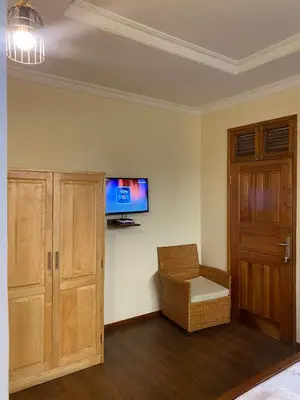 a room with a tv on the wall and a chair at The Black Mamba in Arusha
