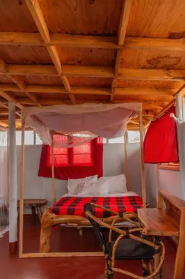 a bed in a room with a wooden ceiling at Naramatisho Women's Centre in Makuyuni