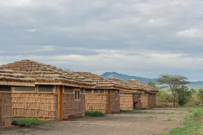 a row of wooden buildings with thatched roofs at Naramatisho Women's Centre in Makuyuni
