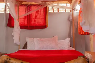 a bedroom with a canopy bed with red sheets at Naramatisho Women's Centre in Makuyuni