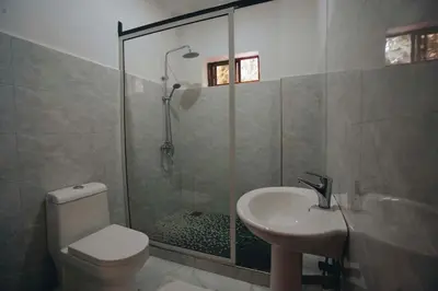 a bathroom with a shower and a toilet and a sink at Naibor Villa in Themi