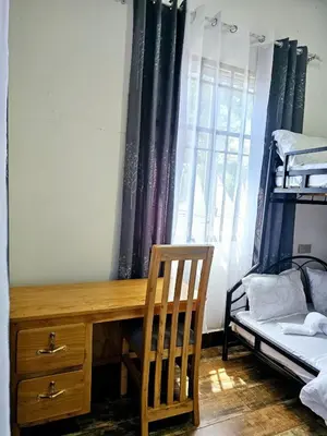 a bedroom with a desk and a bed and a window at Kinyanjui's homes 004 in Kirua