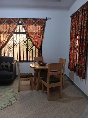 a living room with a table and chairs and a window at Nyumbani House in Mto wa Mbu