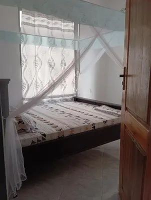 an empty bed in a room with a window at Nyumbani House in Mto wa Mbu