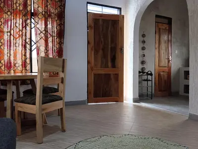 a room with a table and a chair and a door at Nyumbani House in Mto wa Mbu