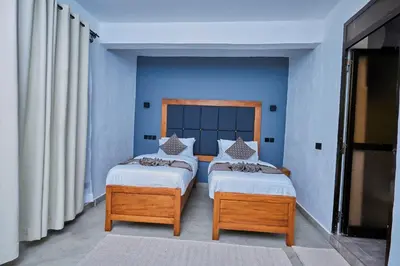 two beds in a room with blue walls at Njiro Luxury in Arusha