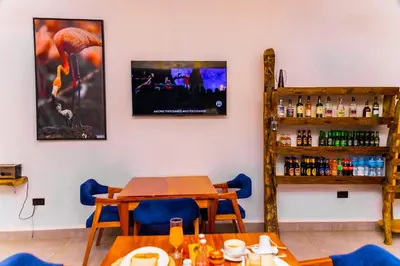 a dining room with a table and a shelf with bottles at Lastanza Safari Lodge in Moshi