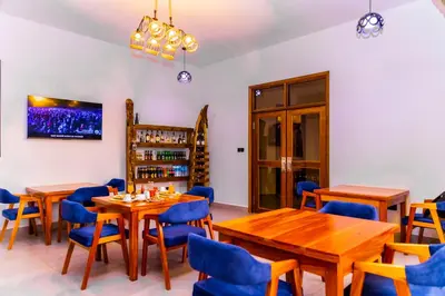 a restaurant with wooden tables and blue chairs at Lastanza Safari Lodge in Moshi