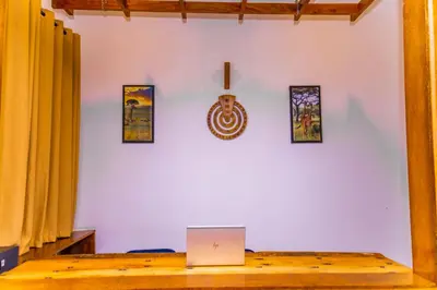 a laptop computer sitting on a wooden table with pictures on the wall at Lastanza Safari Lodge in Moshi