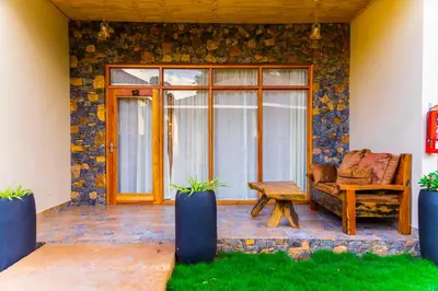 a patio with a couch and a table and a window at Lastanza Safari Lodge in Moshi
