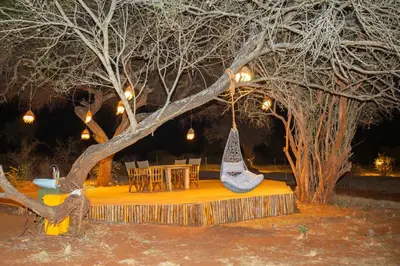 a table and chairs under a tree at night at Shibam Campsite in Naberera