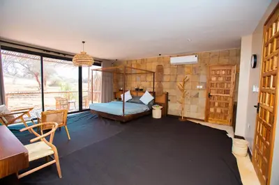 a bedroom with a bed and a table and chairs at Shibam Campsite in Naberera