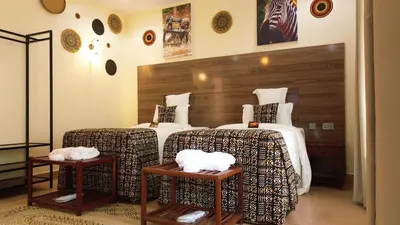 a hotel room with two beds and two tables at Sunset Retreat Hotel in Arusha
