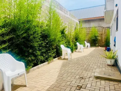 three white chairs sitting on a brick patio at Sunset Retreat Hotel in Arusha