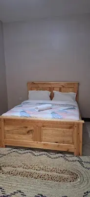 a wooden bed with two pillows on it in a bedroom at African Royal Homestay karatu in Karatu