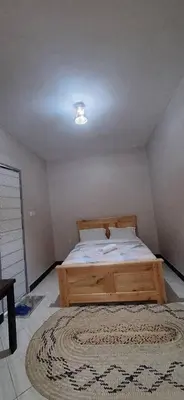 a bedroom with a wooden bed with a rug at African Royal Homestay karatu in Karatu