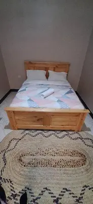 a bedroom with a wooden bed with a rug on the floor at African Royal Homestay karatu in Karatu