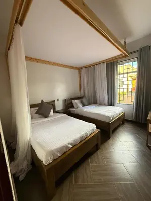 a bedroom with two beds and a window at Cj VILLA in Karatu