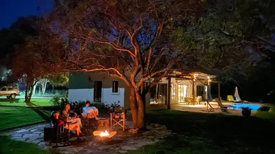 a family sitting around a table under a tree at night at Asama House in Usa