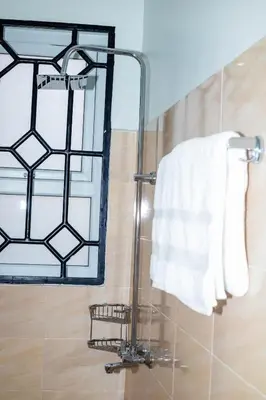 a bathroom with a shower with a mirror and a towel at FM Moshono Apartment in Arusha