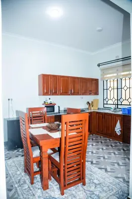 a kitchen with a wooden table and chairs at FM Moshono Apartment in Arusha