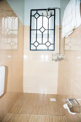 a bathroom with a shower with a window and a sink at FM Moshono Apartment in Arusha
