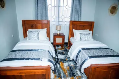 a bedroom with two beds and a window at FM Moshono Apartment in Arusha