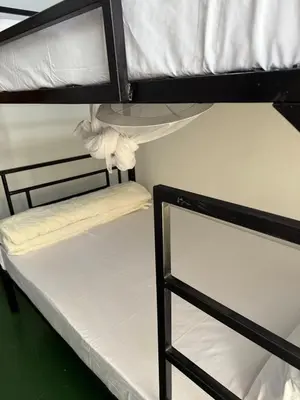 two bunk beds in a room with white sheets at At Chilala's in Arusha