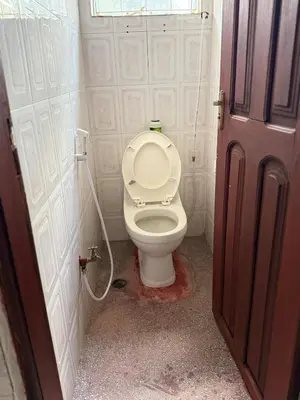 a bathroom with a white toilet with a hose at At Chilala's in Arusha