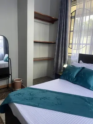 a bedroom with a bed with blue pillows and a window at Famurest in Nkoanrua