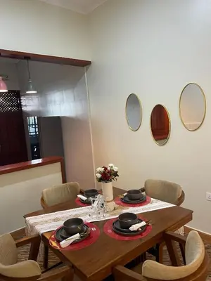 a dining room table with chairs and mirrors on the wall at Famurest in Nkoanrua