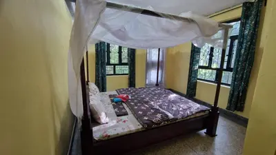 a small bed with a canopy in a room with windows at Kilimanjaro Village Hotel
