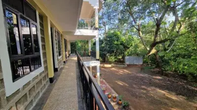 a porch of a building with a fence and a tree at Kilimanjaro Village Hotel