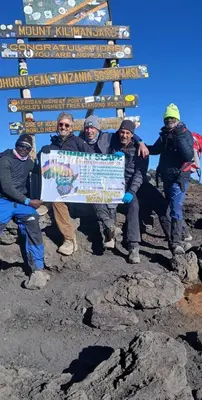 a group of people holding a large sign on a mountain at Summit Scape Adventures Safaris Limited in Arusha