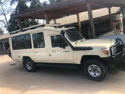 a white jeep parked in front of a building at Summit Scape Adventures Safaris Limited in Arusha