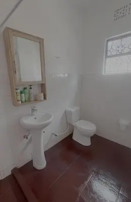 a white bathroom with a sink and a toilet at John's Place in Arusha