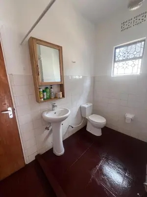 a bathroom with a sink and a toilet and a mirror at John's Place in Arusha