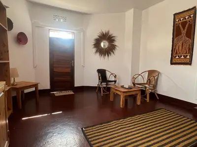 a living room with chairs and a table and a door at John's Place in Arusha