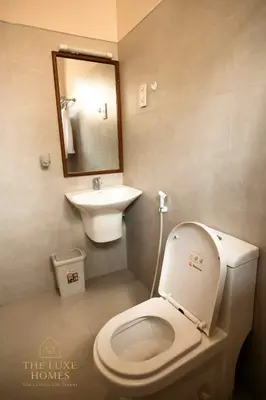 a bathroom with a white toilet and a sink at The Luxe Homes 3BR Luxury Stay in Tuvaila