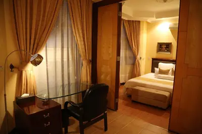 a bedroom with a bed and a desk and a chair at Gold Crest Hotel - Arusha in Arusha
