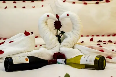 two towel swans making a heart with a bottle of champagne at Gold Crest Hotel - Arusha in Arusha