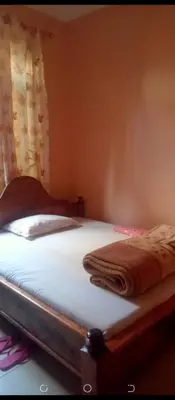 a bed in a bedroom with a blanket on it at Latricia Home Stay in Moshi