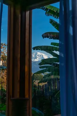 a view of a snow covered mountain through a window at Kilimani Villa in Moshi