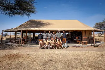 a group of men standing in front of a building at Mawe Tented Camp in Serengeti